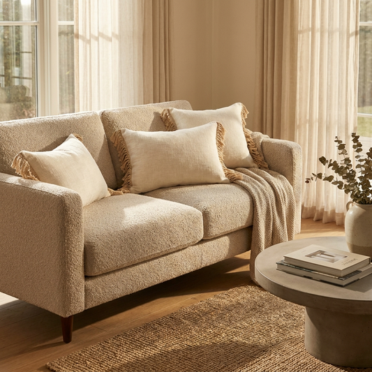 Neutral linen throw pillow covers with tassel trim on a boucle sofa
